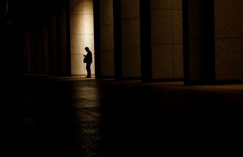 FILE PHOTO: A man is silhouetted at an entrance of a commercial building at closing hour at a financial district in Tokyo