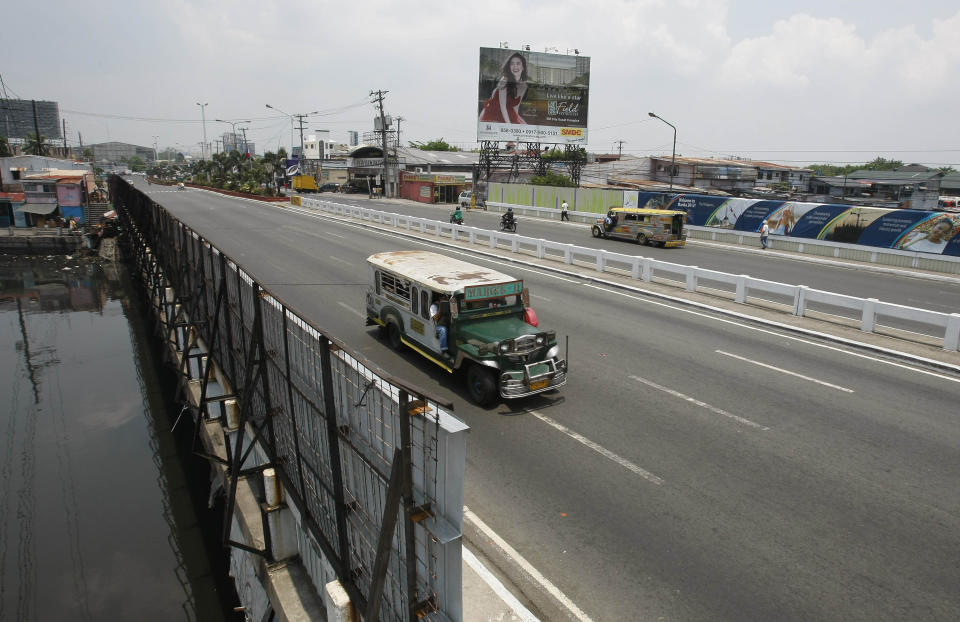 Passenger "jeepneys", modified jeeps, drive past walls covered with tarpaulin posters of the ongoing 45th Annual Board of Governors meeting of the Asian Development Bank at suburban Pasay city south of Manila, Philippines, Thursday May 3, 2012. Delegates attending the international conference of the ADB in the Philippines capital may not see what they came to discuss: abject poverty. The makeshift, temporary walls on both sides of the bridge on a road from the airport to downtown Manila, hides a sprawling slum along a garbage-strewn creek. (AP Photo/Bullit Marquez)