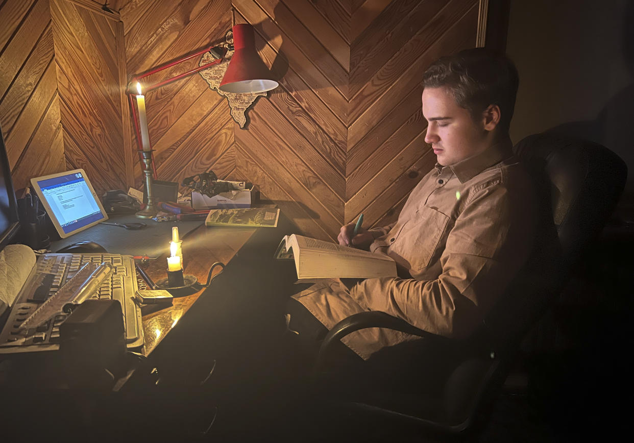 Danylo, 17 has an online biology lesson by candlelight in the village of Start Petrivtsi close to Kyiv, Ukraine, Thursday, Nov. 3, 2022. Rolling blackouts because of Russia's rocket attacks are increasing across Ukraine as the government rushes to stabilize the energy grid and repair the system ahead of winter. (AP Photo/Efrem Lukatsky)