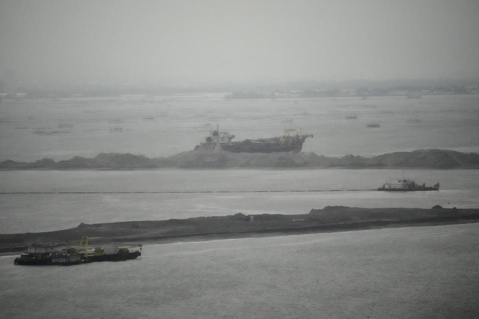 Barges are seen beside reclamation sites in the rain in Manila bay, Philippines on Wednesday, Aug. 2, 2023, The United States expressed concerns over major reclamation projects near its heavily secured embassy, which sits on one edge of Manila Bay, due to the involvement of a blacklisted Chinese company, the U.S. Embassy said Wednesday. (AP Photo/Aaron Favila)