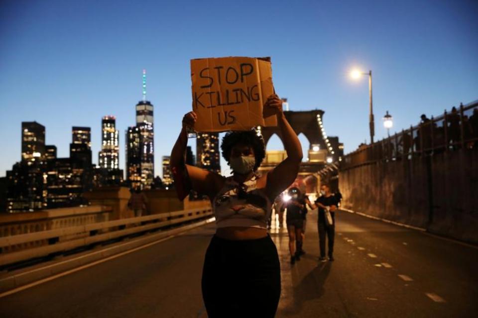 Una mujer sostiene una pancarta que dice Dejad de matarnos durante una protesta en el puente de Brooklyn de Nueva York el 31 de mayo. (Foto: Caitlin Ochs / Reuters).