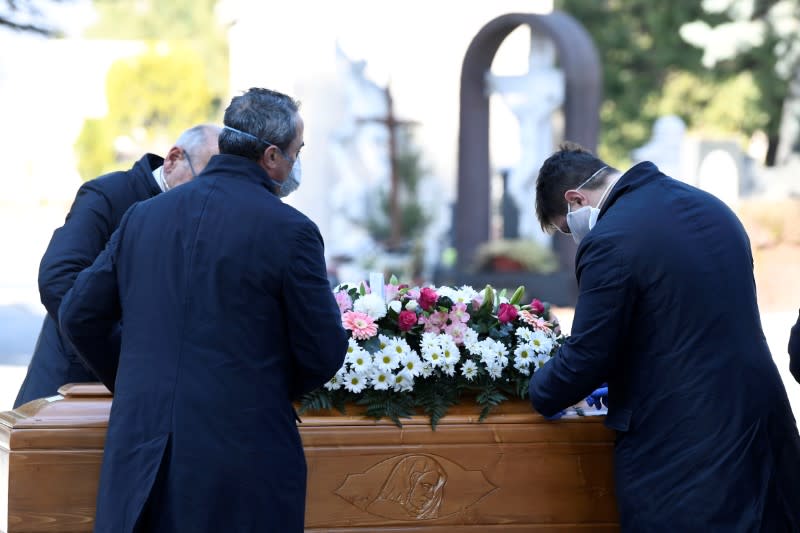 FILE PHOTO: Cemetery workers and funeral agency workers in protective masks transport a coffin of a person who died from coronavirus disease (COVID-19), into a cemetery in Bergamo