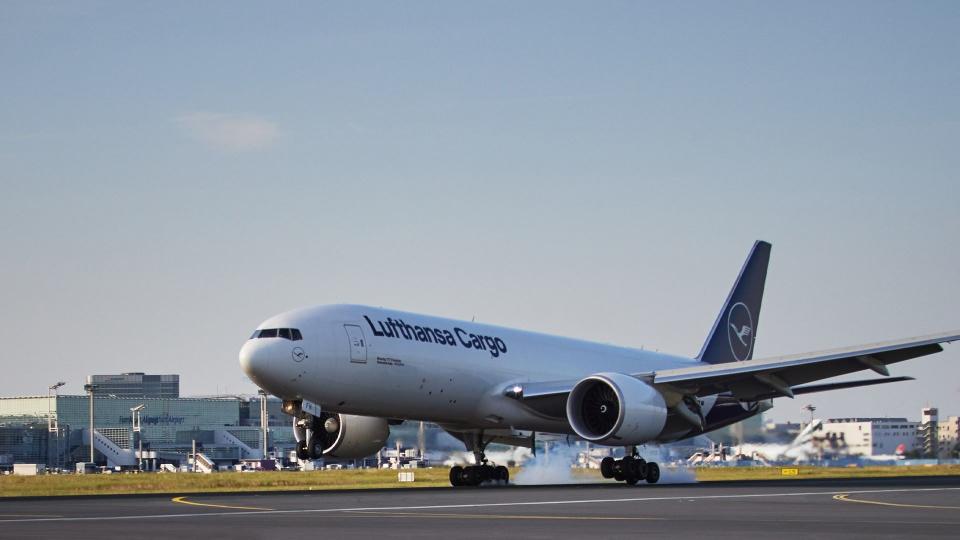 Blue-tailed Lufthansa Cargo jet touches down on a runway.