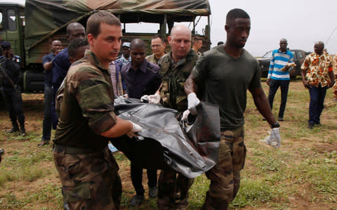 French soldiers and rescuers carry a body after a propeller-engine cargo plane crashed in the sea near the international airport in Ivory Coast's main city, Abidjan, October 14 - Credit: REUTERS