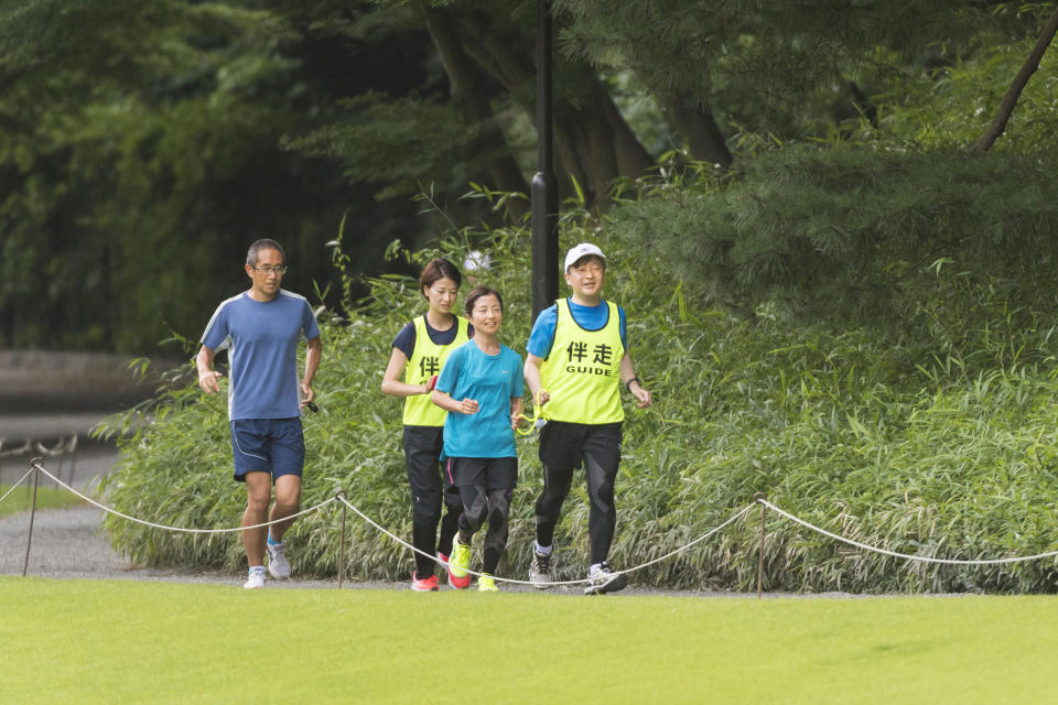 In this June 26, 2018, photo provided by the Imperial Household Agency of Japan, Japan's Crown Price Naruhito, right, guides Rio Paralympics women's T12 marathon silver medalist Misato Michishita as they run together at Akasaka Imperial Garden in Tokyo. Naruhito celebrates his 59th birthday on Saturday, Feb. 23, 2019. (Imperial Household Agency of Japan via AP)