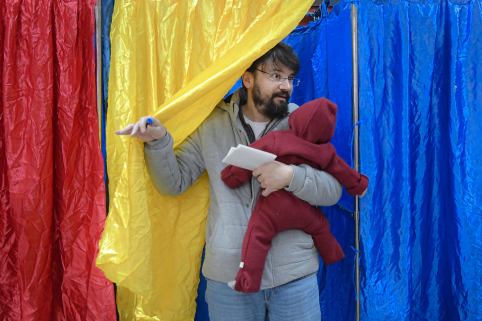 A man holds as he exits a voting cabin in Bucharest, Romania, Sunday, Nov. 24, 2019. Romanians are voting in a presidential runoff election in which incumbent Klaus Iohannis is vying for a second term, facing Social Democratic Party leader Viorica Dancila, a former prime minister, in Sunday's vote. (AP Photo/Andreea Alexandru)