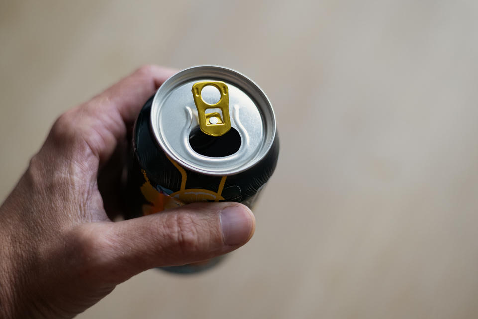 a man holding an open soda can