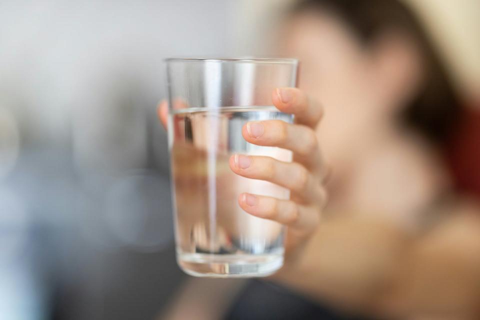 A hand holds a glass of water.