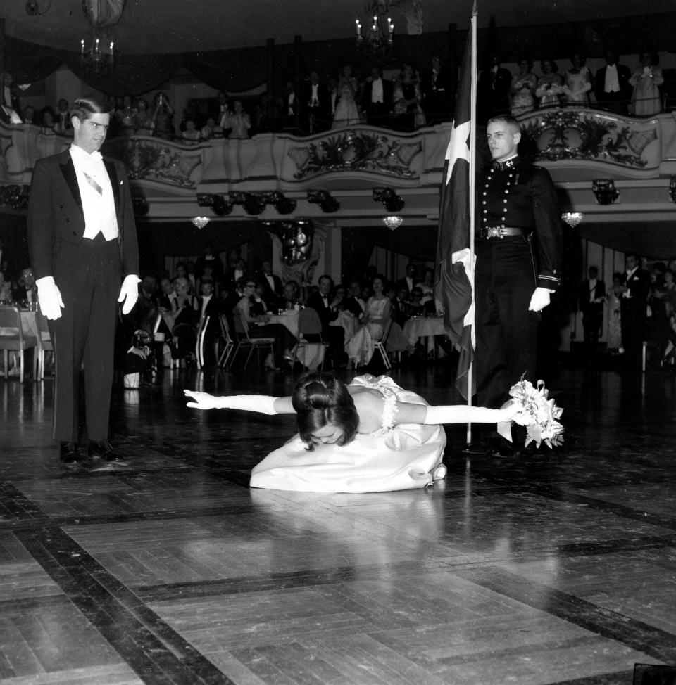 Marialice Sue Shivers, daughter of former Texas governor, bows into society at the International Debutante Ball in New York's Astor Hotel on Dec. 29, 1965.  The Texas flag is held by her honorary military escort, a midshipman from the U.S. naval academy. (AP Photo)