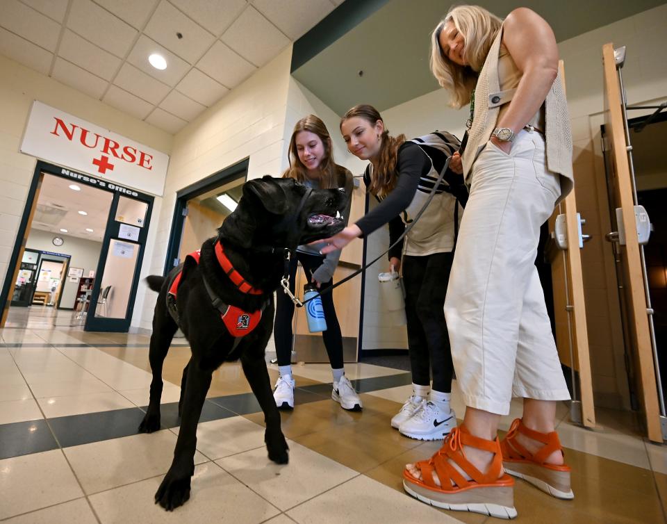 NEADS dog J.D. gets attention from freshmen Dessa Demears, left, and Emma Haffly as the dog's owner, assistant principal Beth Johnson, looks on.