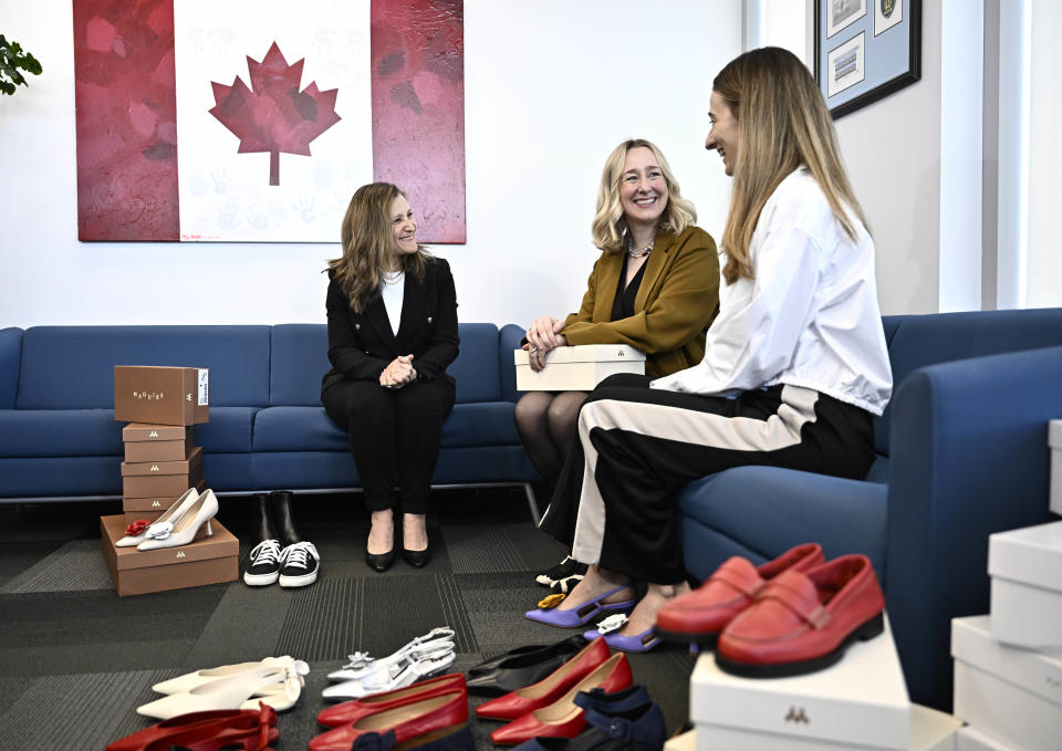 Deputy Prime Minister and Minister of Finance Chrystia Freeland speaks with Myriam Belzile-Maguire, second from right, and Romy Belzile-Maguire, right, founders of direct-to-consumer footwear company Maguire, after selecting her new pair of shoes at a pre-budget photo op in her office in Ottawa, Monday, April 15, 2024. THE CANADIAN PRESS/Justin Tang