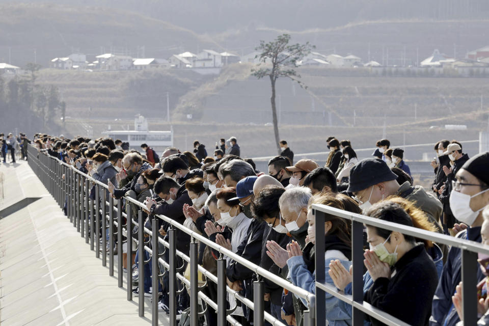 People observe a moment of silence at 2:46 p.m., the moment the earthquake struck in Rikuzentakata, Iwate prefecture on Saturday, March 11, 2023. Japan on Saturday marked the 12th anniversary of the massive earthquake, tsunami and nuclear disaster with a minute of silence, as concerns grew ahead of the planned release of the treated radioactive water from the wrecked Fukushima nuclear plant and the government's return to nuclear energy. (Kyodo News via AP)