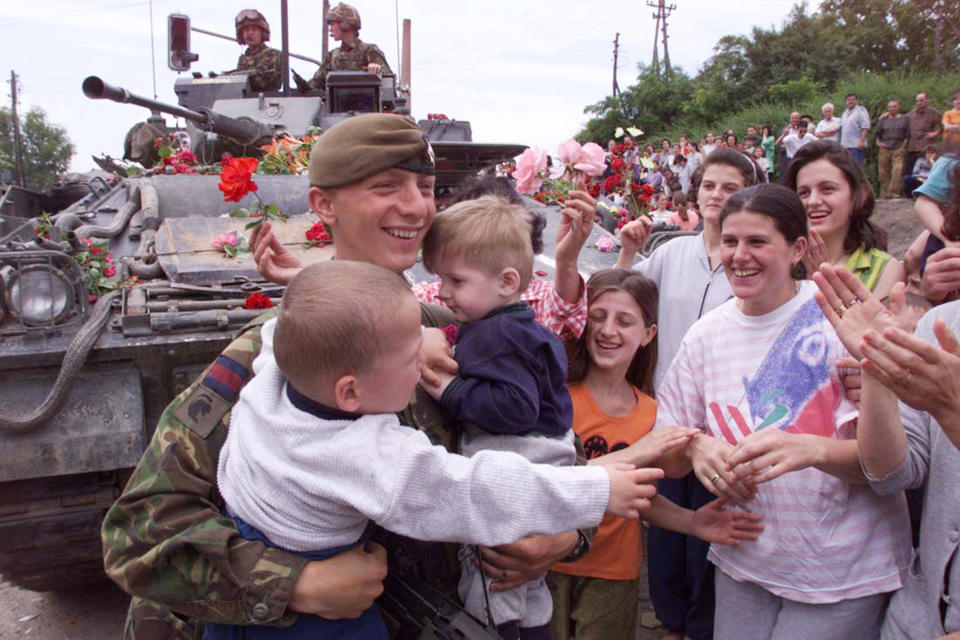 FILE - In this Sunday June 13, 1999 file photo, a British NATO soldier holds two ethnic Albanian children as the Albanian population of Pristina greet NATO troops as they enter various parts of the city. It’s exactly 20 years since NATO forces set foot in the former Yugoslav province, after an allied bombing campaign ended Serbia’s bloody crackdown on an insurrection by the majority ethnic Albanian population in Kosovo _ revered by Serbs as their historic and religious heartland. (AP Photo/Santiago Lyon, File)