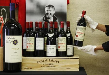 An employee poses with a selection of fine and rare wines owned by retired Manchester United boss Alex Ferguson, at Christie's auction house in London April 14, 2014. REUTERS/Luke MacGregor