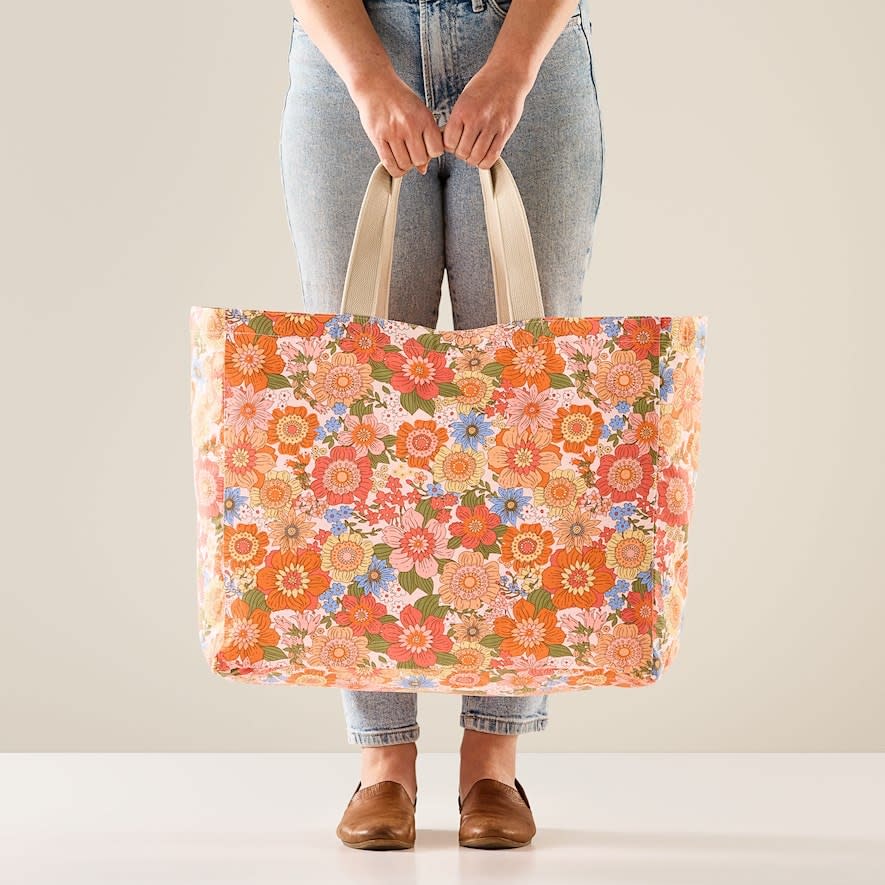 A woman holding Adairs Retro Floral Pink Canvas Beach Bag in both hands 