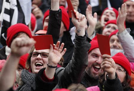 Protesters wearing red caps, the symbol of protest in Brittany, and waving red cards as they take part in a demonstation to maintain jobs in the region and against an "ecotax" on commercial trucks, in Carhaix, western France, November 30, 2013. REUTERS/Mal Langsdon