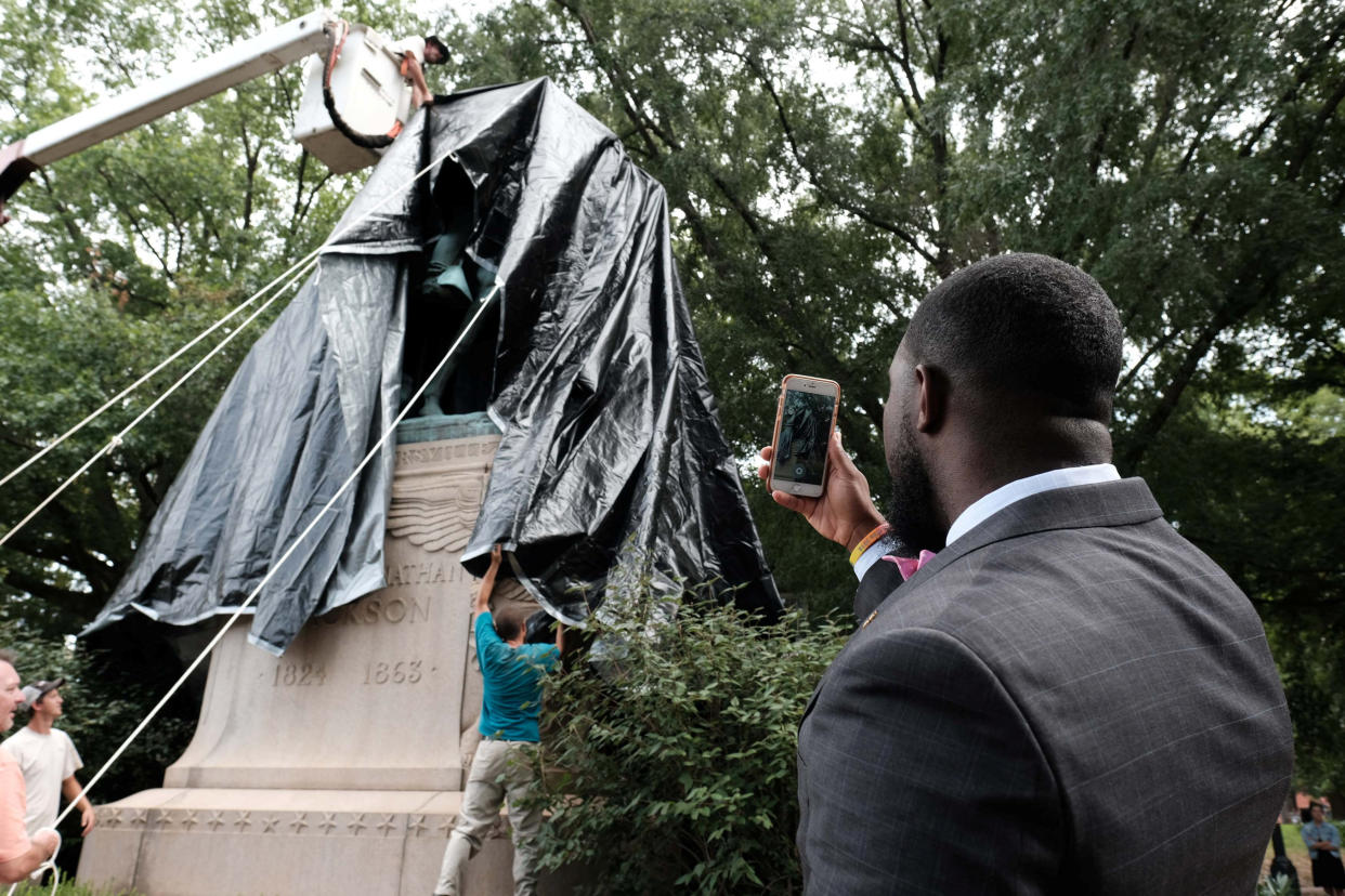 The statue of Confederate General Thomas "Stonewall" Jackson is shown covered in black tarp as Dr. Wes Bellamy, the vice mayor of Charlottesville, takes a photo in the Virginia city on Wednesday. (Photo: Justin Ide / Reuters)