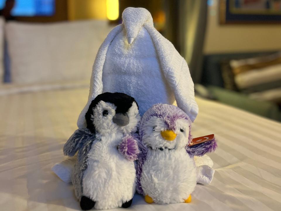 stuffed penguins and penguin shaped towel on bed