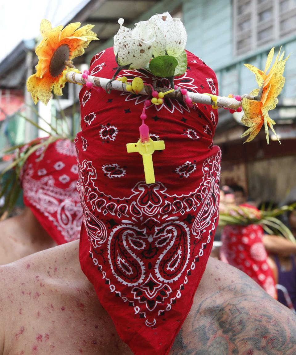 Masked devotee prays outside a chapel during a Maundy Thursday ritual by penitents to atone for sins in Angeles