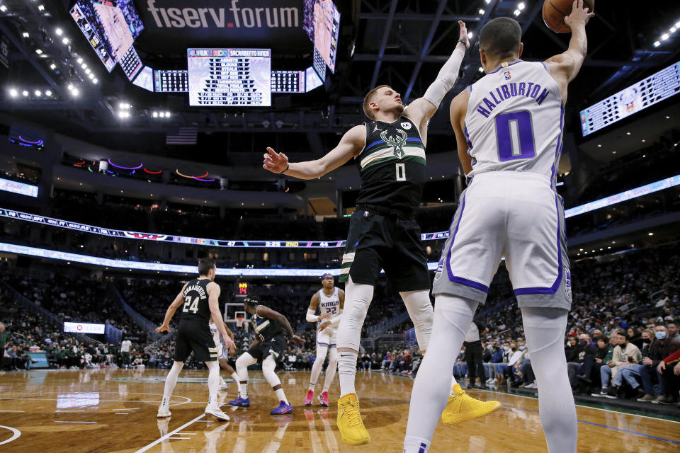 Milwaukee Bucks guard Donte DiVincenzo (0) defends against a pass by Sacramento Kings guard Tyrese Haliburton (0) during the first half of an NBA basketball game Saturday, Jan. 22, 2022, in Milwaukee. (AP Photo/Jon Durr)