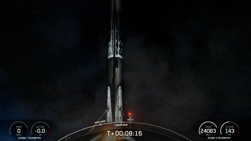 A black and white spacex falcon 9 rocket first stage sits on the deck of a ship at sea at night.