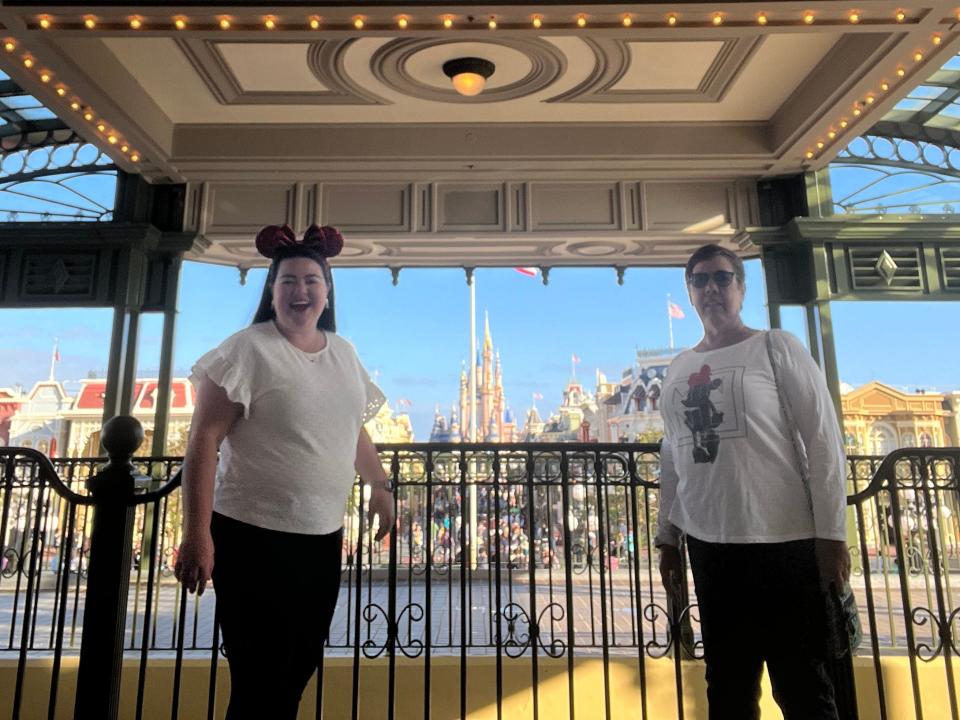 megan and her mom posing at the train station in magic kingdom with the castle in the background