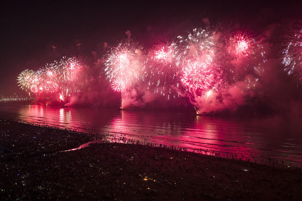People bring in the New Year as they watch fireworks explode over Santos Bay, in Santos, Brazil, early Sunday, Jan. 1, 2023. (AP Photo/Matias Delacroix)