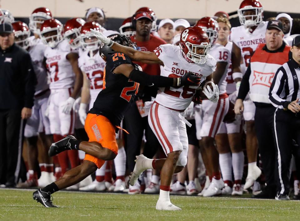 Oklahoma running back Kennedy Brooks (26) works to escape a tackle by Oklahoma State cornerback Jarrick Bernard-Converse (24) during the first half at Boone Pickens Stadium.