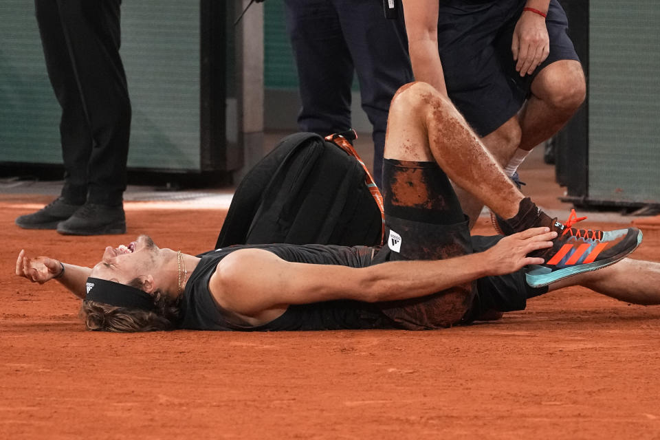 Germany's Alexander Zverev grimaces in pain and shows his ankle after falling as he plays Spain's Rafael Nadal, during their semifinal match of the French Open tennis tournament at the Roland Garros stadium Friday, June 3, 2022 in Paris. Alexander Zverev stopped playing because of an injury. (AP Photo/Michel Euler)