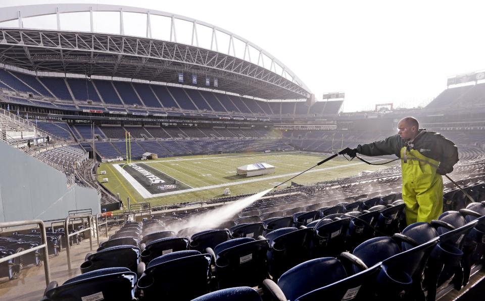 A worker, who declined to be identified, cleans seats at CenturyLink Field in preparation for the NFL football NFC championship in Seattle, Wednesday, Jan. 15, 2014. The Seattle Seahawks play the San Francisco 49ers on Sunday. (AP Photo/Elaine Thompson)
