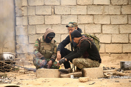 Members of the Lions of the Tigris, a group of Sunni Arab fighters and part of the Hashid Shaabi (Popular Mobilization Comimittee) warm themselves near the fire during pause in a military operation against Islamic State militants in Shayyalah al-Imam, Iraq November 30, 2016. REUTERS/Thaier Al-Sudani