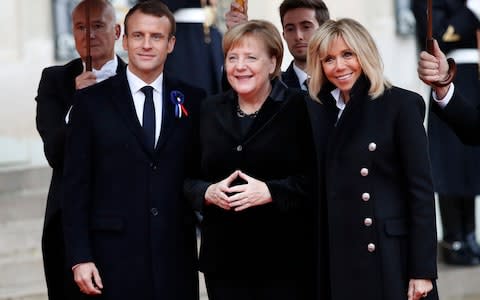 German Chancellor Angela Merkel being greeted by French President Emmanuel Macron and his wife Brigitte Macron as she arrived at the Elysee Palace in Paris this morning - Credit: AP