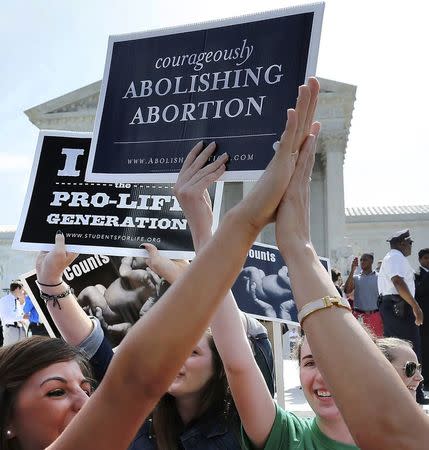 Anti-abortion demonstrators high five as the ruling for Hobby Lobby was announced outside the U.S. Supreme Court in Washington June 30, 2014. REUTERS/Jonathan Ernst