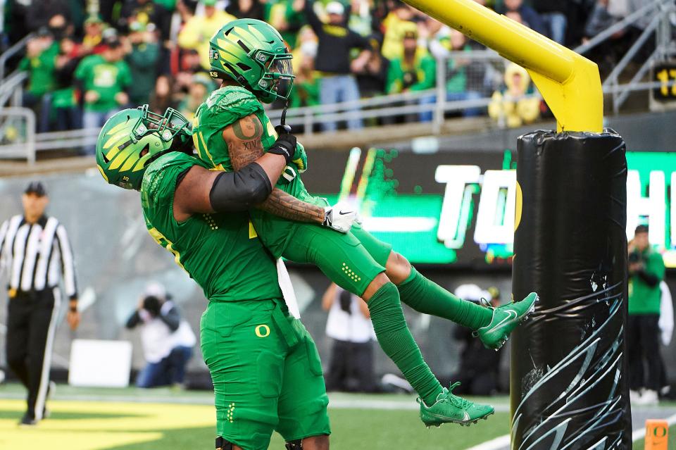 Nov 27, 2021; Eugene, Oregon, USA; Oregon Ducks offensive lineman Steven Jones (74) lifts wide receiver Kris Hutson (14) in celebration after a touchdown reception during the second half at Autzen Stadium. The Ducks won 38-29. Mandatory Credit: Troy Wayrynen-USA TODAY Sports