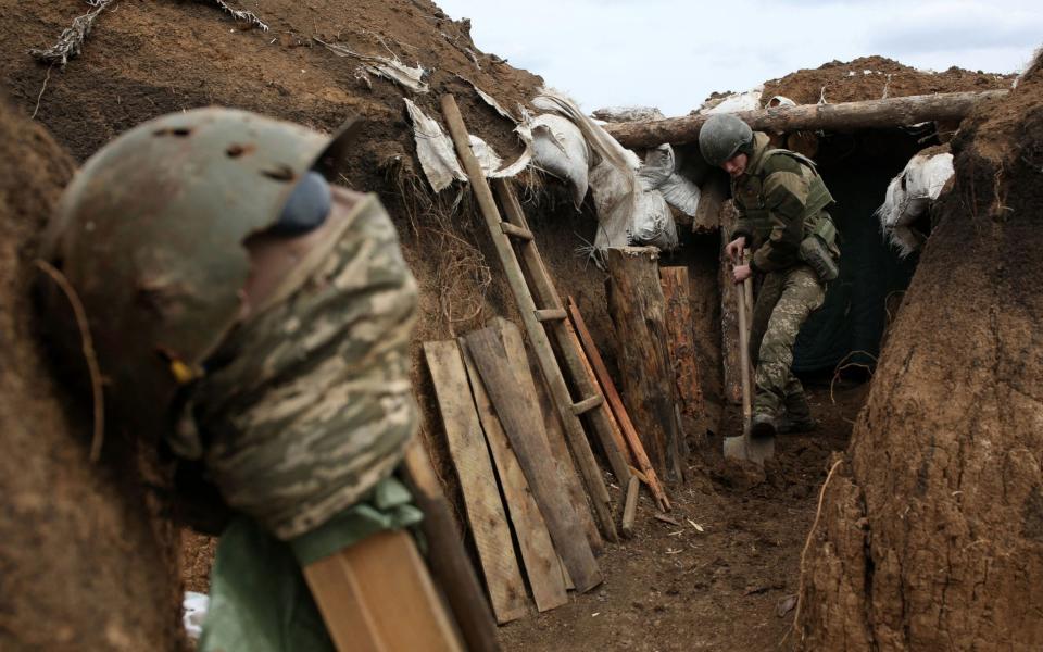 An Ukrainian serviceman digs the ground of a trench as he stands at his post on the frontline on April 8 - AFP