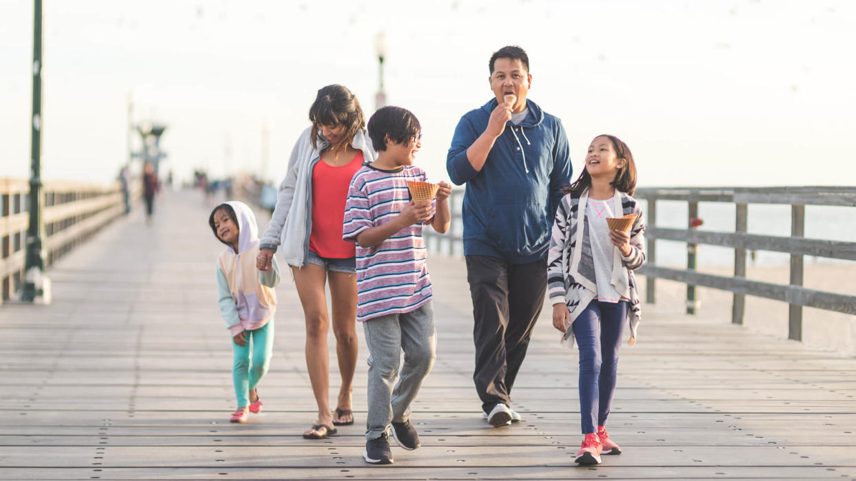 Two Filipino parents and their three children enjoy huge waffle ice cream cones on a California boardwalk by the beach.