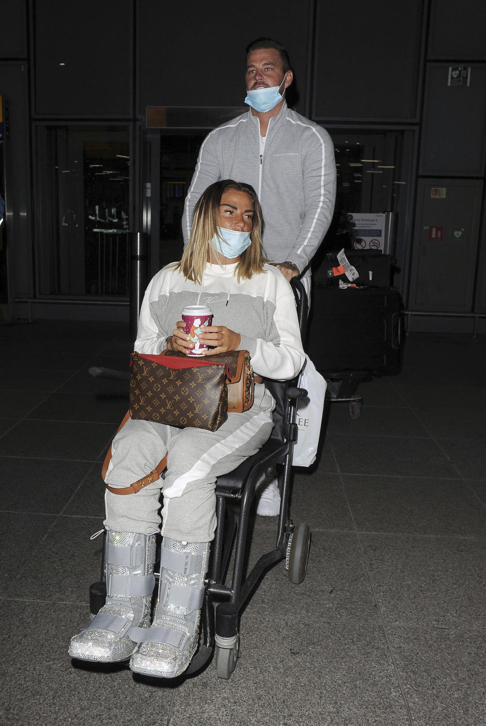 Photo by: zz/KGC-305/STAR MAX/IPx 2020 11/6/20 Katie Price and her boyfriend Carl Woods are seen on November 6, 2020 arriving at Heathrow Airport - returning to England from their holiday in The Maldives. They were not in compliance with strict government guidelines mandated during the worldwide coronavirus pandemic as they both were wearing their face masks improperly as both had their noses exposed. (London, England, UK)