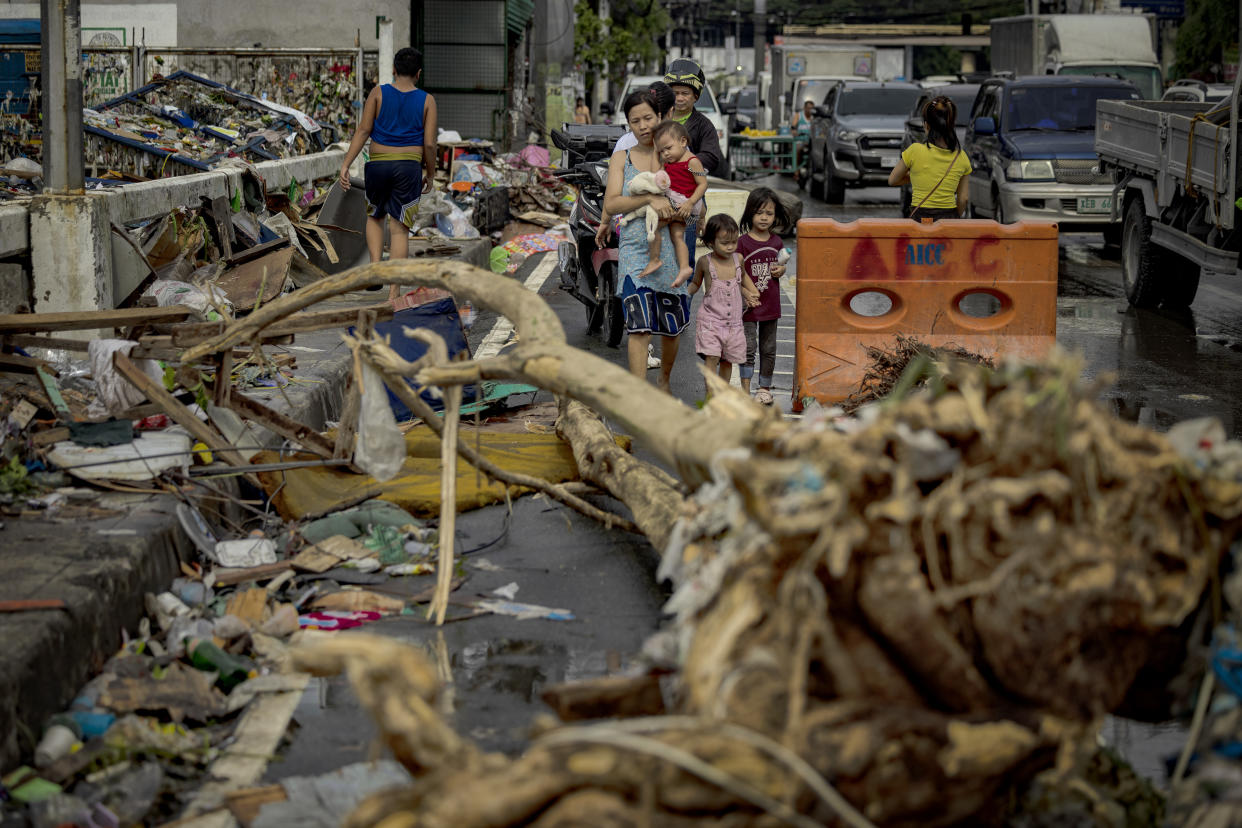 Residents walk past debris brought about by floods caused by Typhoon Gaemi in Manila on Thursday.