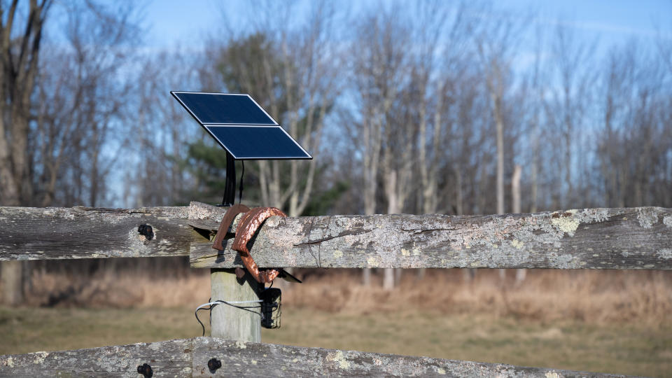 SEHMUA 4G LTE 3rd Gen Cellular Trail Camera and solar panel attached to a fence in a field