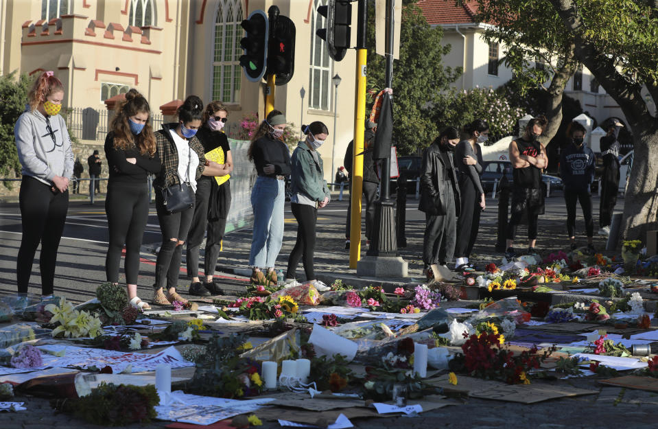 Demonstrators look at placed flowers as they attend a protest outside parliament in Cape Town, South Africa, Wednesday June 3, 2020, over the death of George Floyd, a black man who died after being restrained by Minneapolis police officers on May 25. (AP Photo/Nardus Engelbrecht)