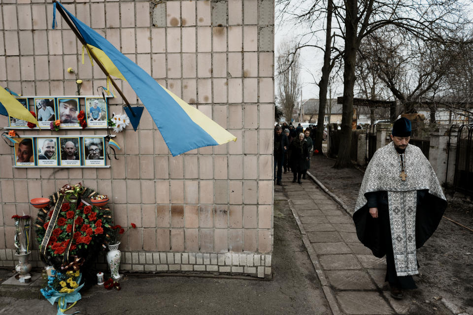 A priest arrives to commemorate the first anniversary of the death of eight men killed by Russian forces in Bucha, Ukraine, Saturday, March 4, 2023. The eight had set up a roadblock on a road in the town in an attempt to prevent Russian troops from advancing, as they swept towards the Ukrainian capital at the start of their invasion. (AP Photo/Thibault Camus)