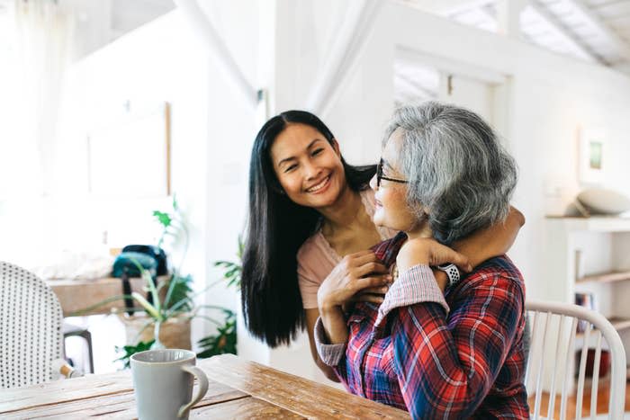 Two women, one older and one younger, smiling and embracing in a home kitchen