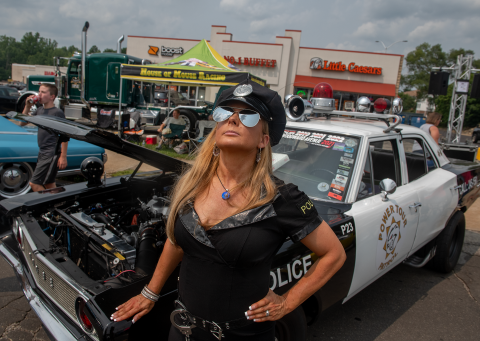 Melanie Sinkie McCavich is dressed as a police officer with a 1968 Dodge Coronet cop car at the 2023 Octane Nights car show in Ravenna .