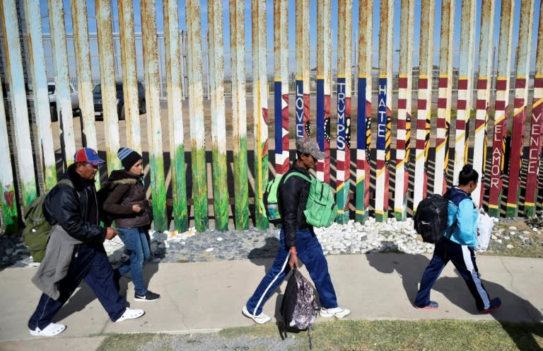 Central American migrants walk along the US-Mexico border fence in Playas de Tijuana, Mexico