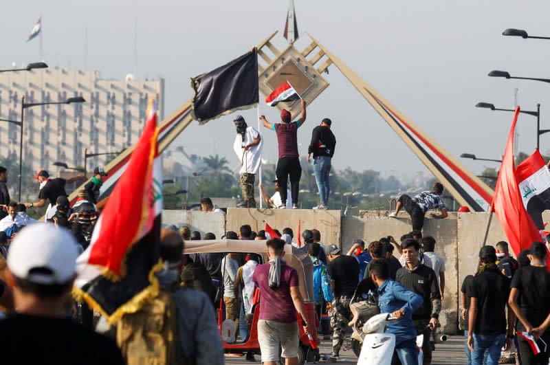 Protesters stand on a concrete wall during a protest over corruption, lack of jobs, and poor services, in Baghdad