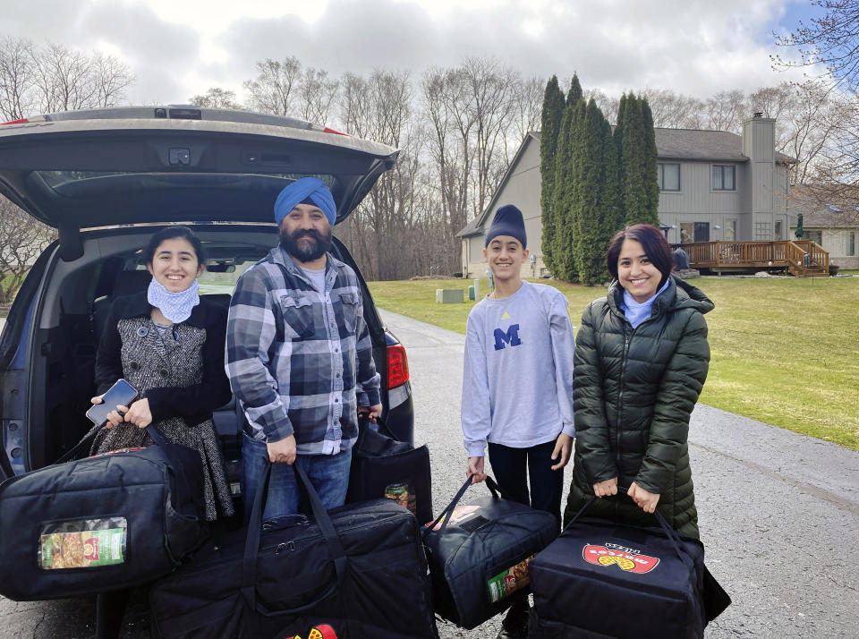 In this April 1, 2020 photo provided by Paramjyoti Kaur Singh, Singh family members Baani, Shalinder, Arjun and Jasveen Kaur pose for a photo before delivering pizzas to health care workers in Detroit. (Paramjyoti Kaur Singh via AP)