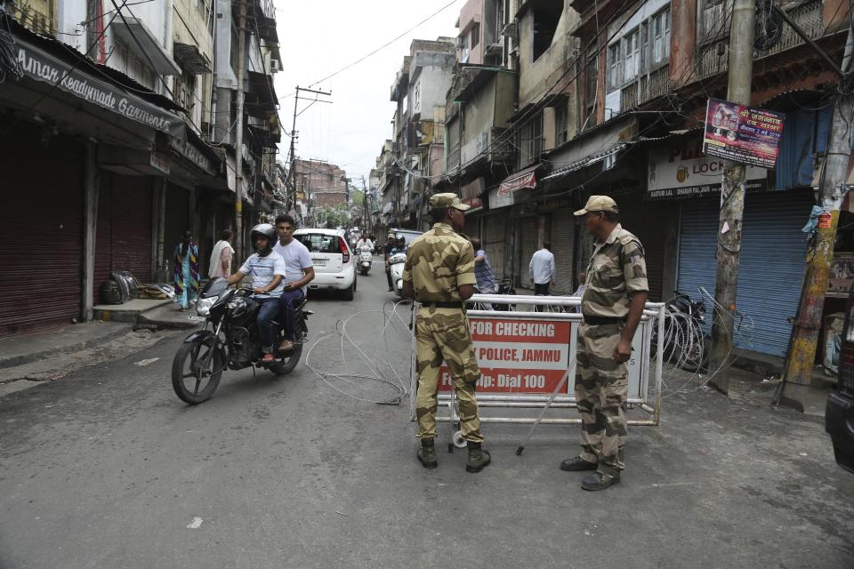 Security officers stand guard near a barricade in Jammu, India, Wednesday, Aug. 7, 2019. Indian lawmakers passed a bill Tuesday that strips statehood from the Indian-administered portion of Muslim-majority Kashmir, which remains under an indefinite security lockdown, actions that archrival Pakistan warned could lead to war. (AP Photo/Channi Anand)