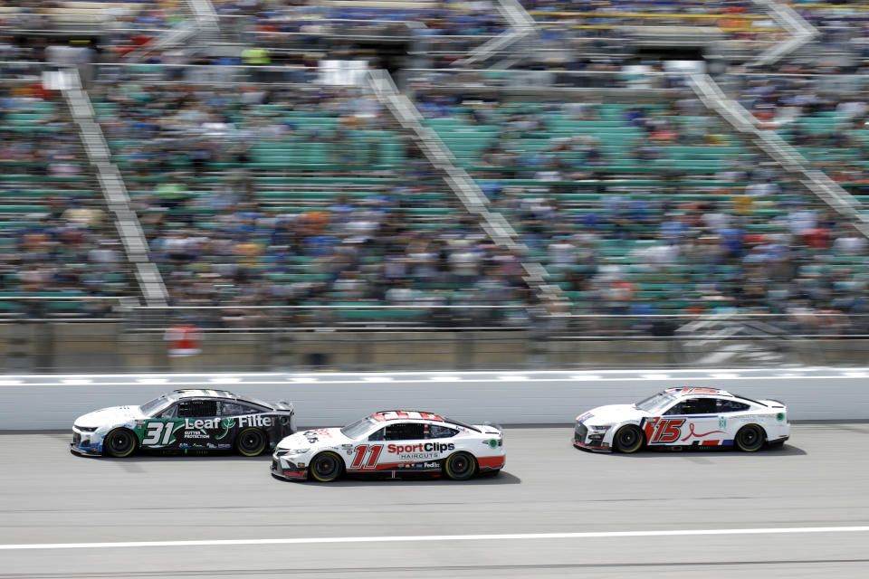 Justin Haley (31), Denny Hamlin (11), and J.J. Yeley (15) head into Turn 1 during a NASCAR Cup Series auto race at Kansas Speedway in Kansas City, Kan., Sunday, May 15, 2022. (AP Photo/Colin E. Braley)