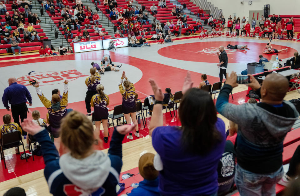 Spencer fans cheer as their team takes on Waverly-Shell Rock during the first sanctioned girls wrestling dual in Iowa history Monday at Dallas Center-Grimes.