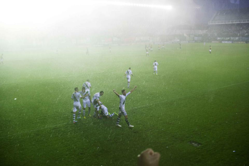 In this Feb. 8, 2014 photo, Banfield players celebrate after their teammate Fabian Noguera scored the second goal against Almirante Brown during a match for the second division of the professional league, during a in a downpour in Buenos Aires, Argentina. Argentines have suffered through a tough summer, with tropical rain that provided no relief from the heat and humidity, people having to throw out rotten food because of rolling power blackouts and soaring oil and gas prices, all amid rising inflation that is making it ever harder to reach the end of the month. The strain is evident on the faces of subway riders and others making their way home in Buenos Aires, where signs of poverty and decay are ubiquitous just beyond the glamorous streets where tourists go. (AP Photo/Rodrigo Abd)